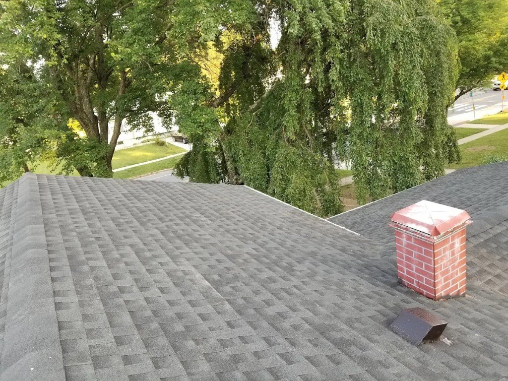 Architectural shingle roof valley with brick chimney cap in Laurel, MD