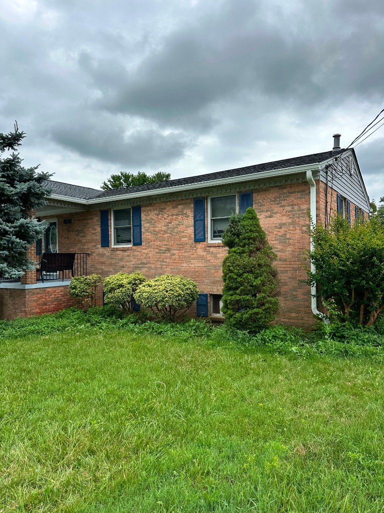Gutter installation on a brick rambler home with blue shutters