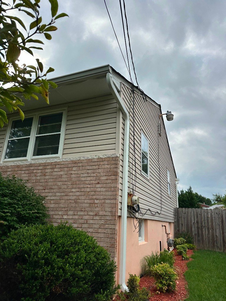 Close-up of new vinyl siding and gutter corner detail against brick